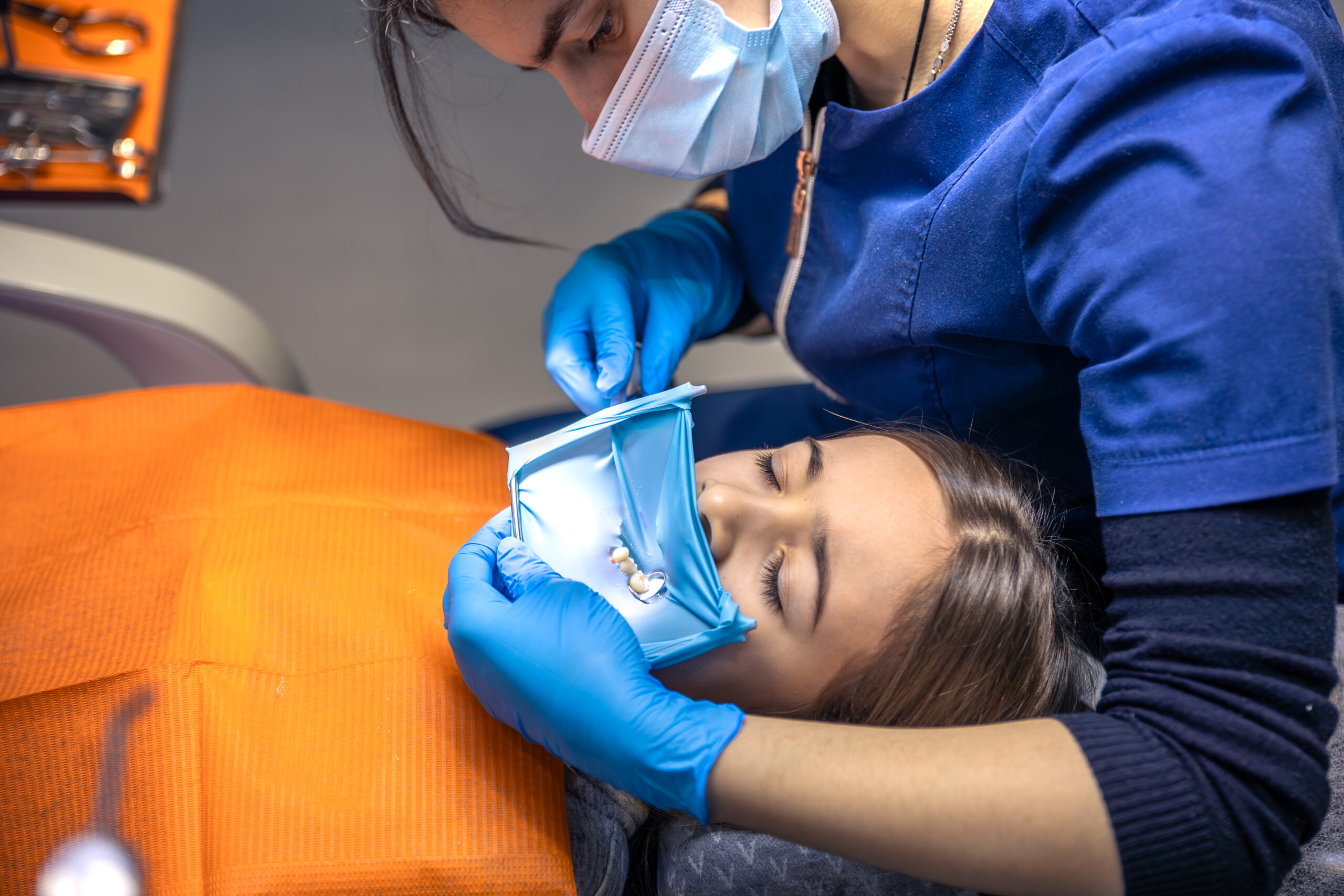 the dentist treats the child's tooth using a rubber dam. close up of tooth treatment.